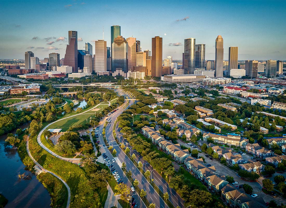 Houston, TX - Aerial View of Homes and Modern Skyscrapers and Commercial Buildings Against a Blue Sky in Houston Texas at Sunset